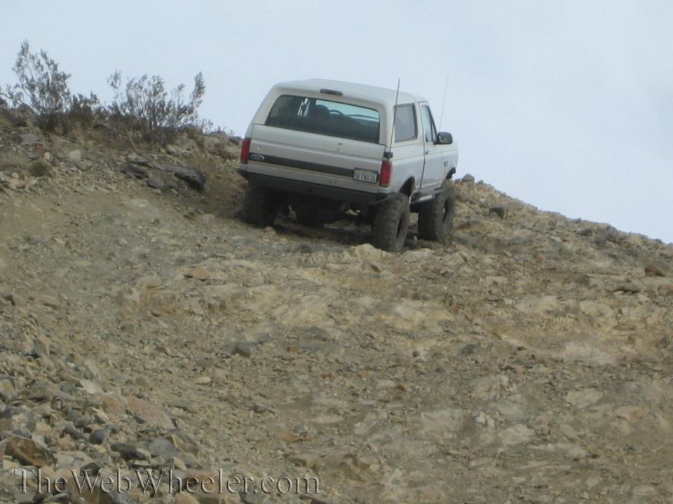 White Ford SUV on a rocky off-road hillclimb with Ford tailgate badge