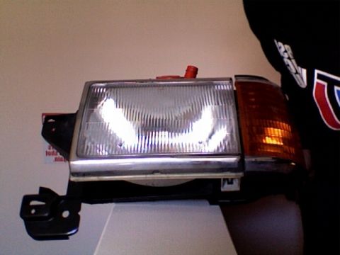 1990 Ford Bronco - This headlight assembly features a clear main lens and an amber turn signal indicator.