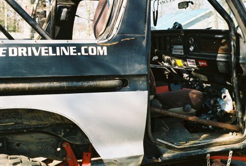 1978 Ford Bronco - Close side view through the doorless opening of a stripped black-and-white 4x4 project, showing the dash with toggle-switch panel, twin shi…