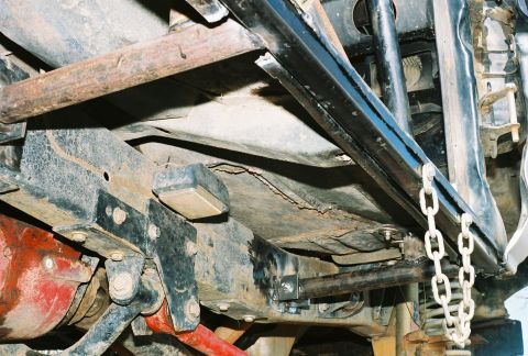 1978 Ford Bronco - Film photo shot from below a 4x4 showing a black tube side bar or rock rail bolted to welded frame brackets under a rusty floor pan and roc…