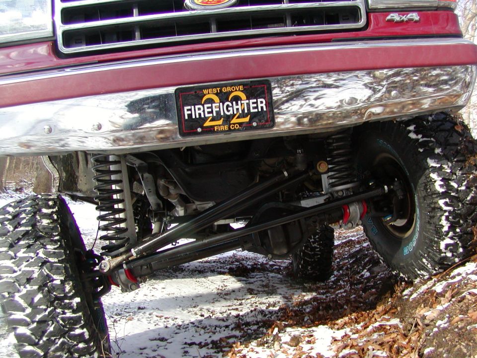 Front grille and bumper of a red Ford F-Series truck with a "Firefighter 22" license plate and off-road suspension