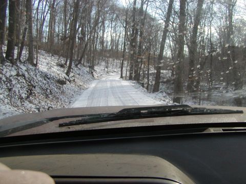 1991 Ford Bronco - View from inside a vehicle as it travels down a snow-covered road through a forest.
