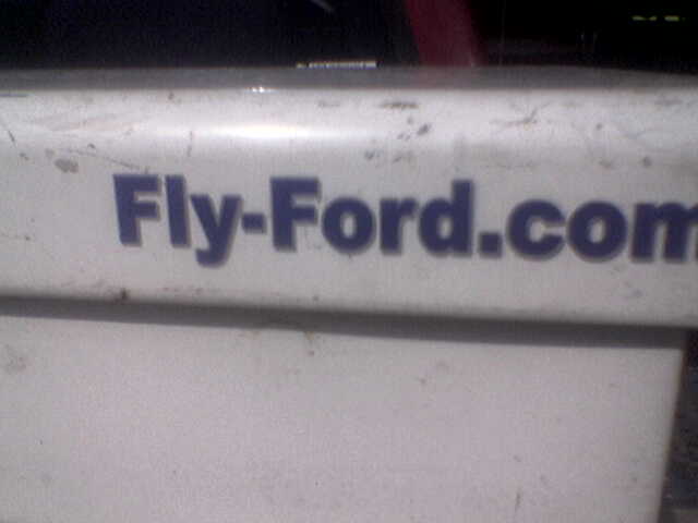 Close-up of text that says Fly-Ford.com on a white surface
