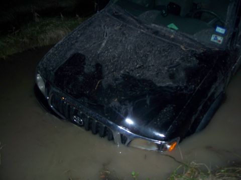 1979 Ford Bronco - This black Toyota Tacoma appears to be stuck in a muddy, water-filled ditch.