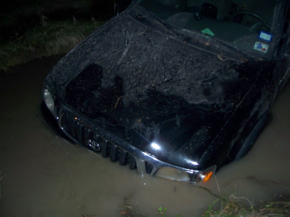 Black Toyota Tacoma stuck in muddy water, front view
