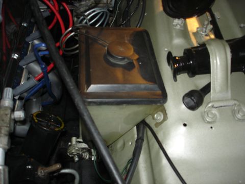 1979 Ford Bronco - Close-up view of the engine bay, focusing on the windshield washer fluid reservoir and various hoses and wires.