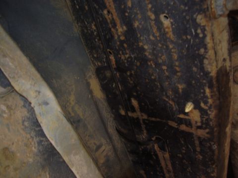 1990 Ford Bronco - Close-up view of the rusty and dirty undercarriage of a vehicle, showing frame rails and suspension components.
