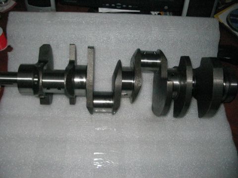1991 Ford Bronco - A metal crankshaft, a key component of an internal combustion engine, is displayed on a white surface.