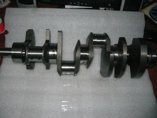 Crankshaft with multiple throws and journals, resting on a white padded surface