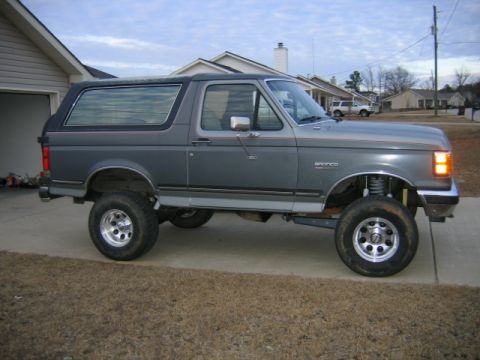 1989 Ford Bronco - A lifted 1989 Ford Bronco is shown from the side in a suburban driveway.