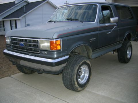 1989 Ford Bronco - This lifted SUV features a two-tone paint scheme with a red accent stripe.