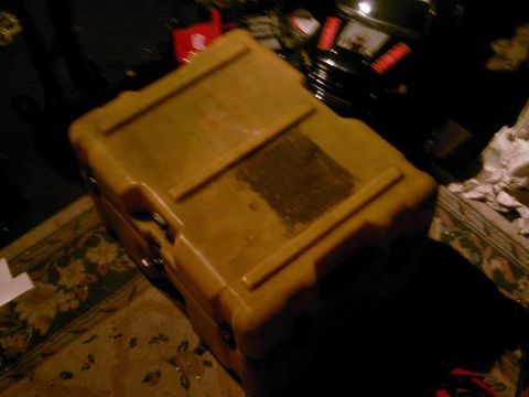 1986 Ford Bronco - A yellow plastic case is placed on a rug in a dimly lit area with debris in the background.