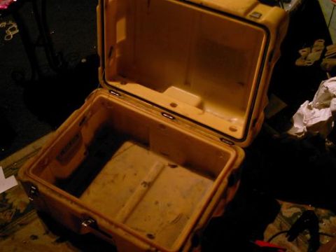 1986 Ford Bronco - An empty, open yellow plastic case sits on a dark surface with some clutter around it.