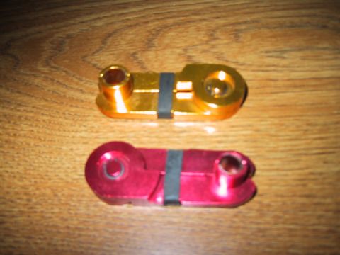 1994 Ford Bronco - Two anodized billet aluminum battery terminal or power-distribution blocks, one gold and one red/pink, each with a black insulating band an…