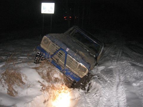 1979 Ford Bronco - This blue off-road vehicle appears to be stuck in a muddy, snowy ditch during a winter night.