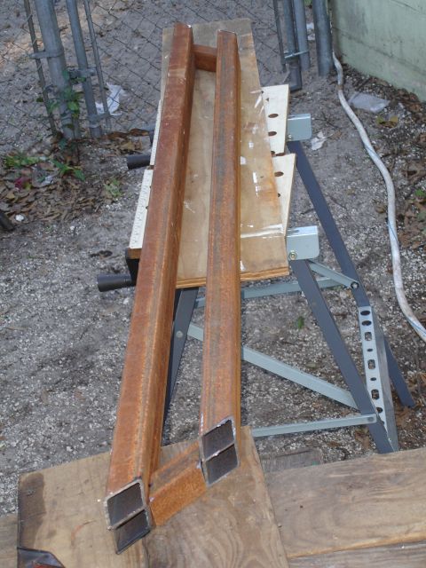 1989 Ford Bronco - Two rusted metal sliders are shown on a workbench, likely for a vehicle.