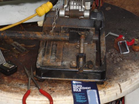 1989 Ford Bronco - Chop saw and various tools on a workbench, including a package of halogen replacement bulbs.