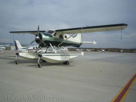 1990 Ford Bronco - high-wing floatplane sits on its pontoons on an airport ramp with other small aircraft parked behind it.