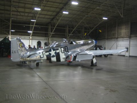 1990 Ford Bronco - bare-metal WWII-style fighter marked with a US star insignia, fuselage codes, and serial number rests in a hangar.
