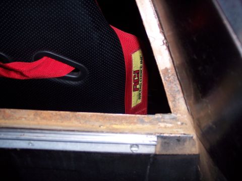 1972 Ford Ranchero - Interior view of a racing seat with a red harness and visible rust on the metal trim.