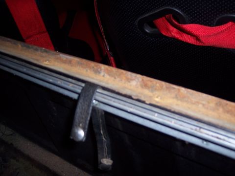 1972 Ford Ranchero - Close-up of a rusted metal bar and seatbelt, likely from a vehicle interior.