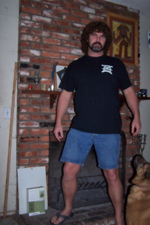 1990 Ford Bronco - A man with a distinctive hairstyle and beard poses in front of a brick fireplace, with a dog visible to the right.