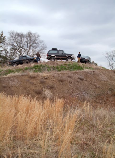 1995 Ford Bronco - Three SUVs are parked on a dirt embankment under an overcast sky, with dry grass in the foreground.