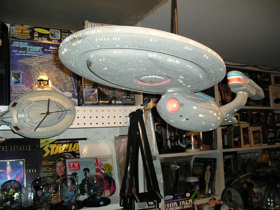 Star Trek model ship hanging above shelves with Star Trek memorabilia, including a clock