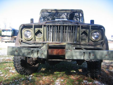 2005 Ford F-250 - A vintage military truck, likely a Kaiser Jeep M715, is parked outdoors with an RV visible in the background.