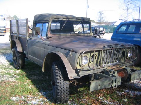 2005 Ford F-250 - An old military truck sits parked outdoors next to other vehicles.