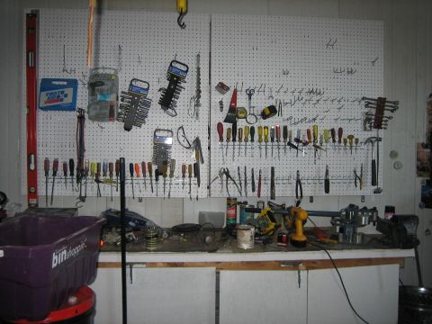 1976 Ford Ranchero - A cluttered workbench displays a variety of tools, including screwdrivers, wrenches, and a drill, organized on a pegboard.