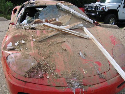 1991 Ford Probe - This red sports car is heavily damaged and covered in debris, with a white Hummer visible behind it.