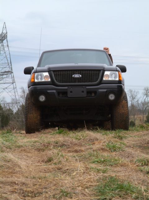 1995 Ford Bronco - Black Ford Ranger pickup truck parked in a grassy, outdoor area with a power line tower in the background.