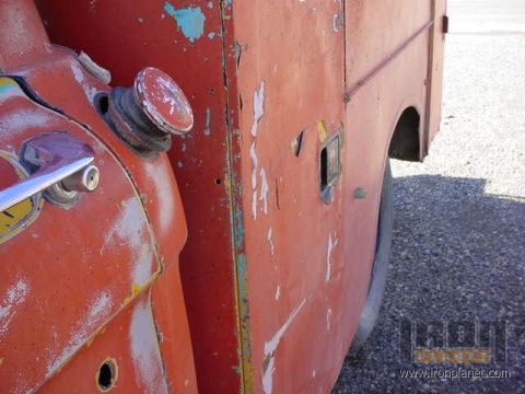 1966 Ford F-250 - Detail of a 1966 Ford F-250's weathered red side panel, showing a chrome door handle and fuel cap.
