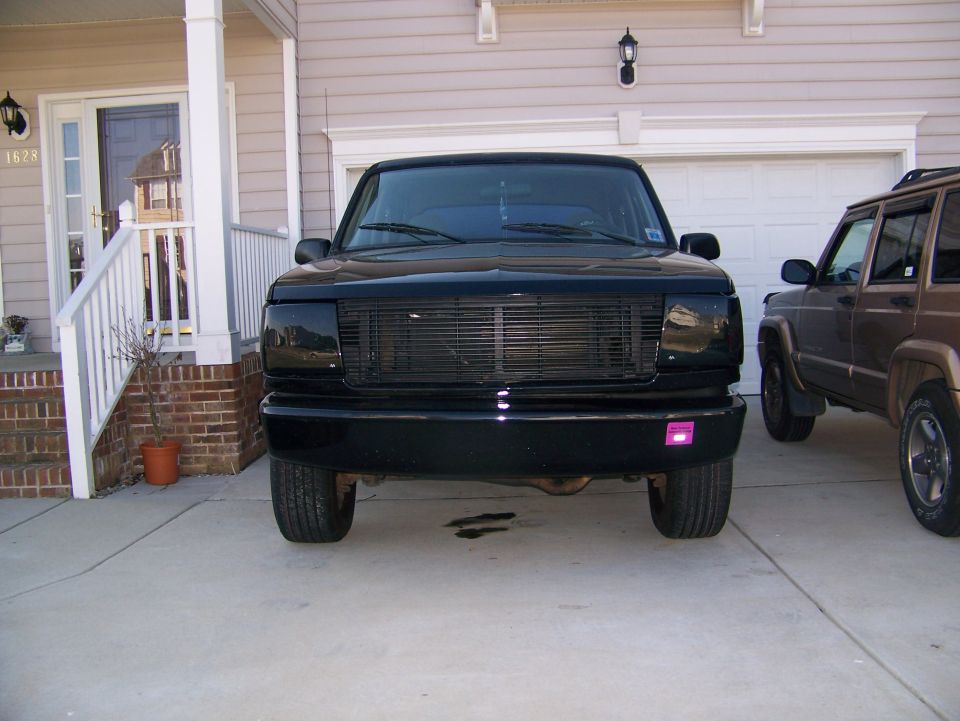 Front view of a black SUV with billet grille in a residential driveway