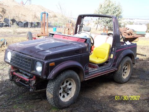 1979 Ford Bronco - This Suzuki Samurai is missing its doors and top, revealing its interior and yellow seats.