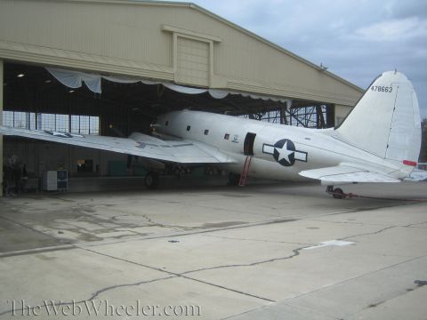 1990 Ford Bronco - large bare-metal vintage transport aircraft with US star insignia and tail number 478683 sits at a hangar entrance.