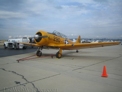1990 Ford Bronco - yellow propeller trainer marked '290' sits on the ramp beside a Chevron fuel truck, with an orange cone in the foreground.