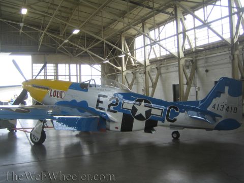 1990 Ford Bronco - silver fighter aircraft marked 'E2-C' and '413410' with a yellow nose and blue trim sits inside a hangar.