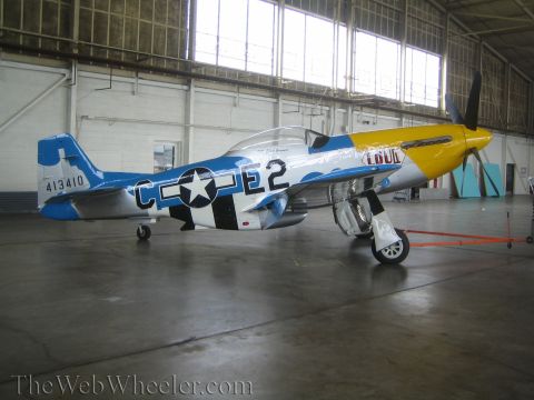 1990 Ford Bronco - silver fighter aircraft with a yellow nose marked 'C E2' and '413410' sits on its tail-down stance inside a bright hangar.
