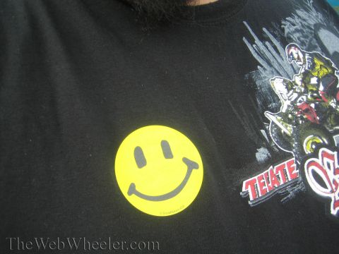 1990 Ford Bronco - black t-shirt worn by a bearded person bears a yellow smiley-face sticker and a motocross rider graphic with red 'TECATE' text.