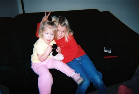 2002 Oldsmobile Aurora - Two girls pose for a photo while sitting on a couch.