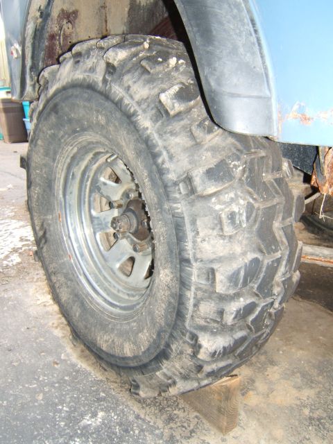 1980 Jeep CJ5 - This image focuses on a heavily treaded tire and the weathered fender of an off-road vehicle.