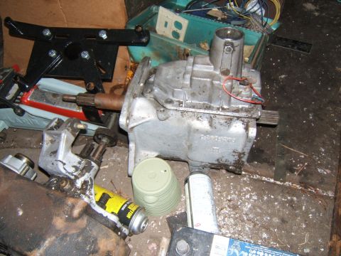 1980 Jeep CJ5 - Close-up of a transmission and associated parts, including a black mounting bracket and a yellow can of lubricant.