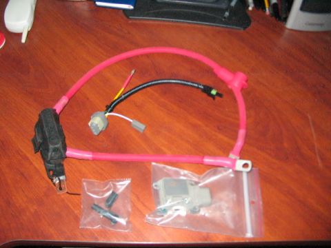 1991 Ford Bronco - A battery cable assembly, including a fuse holder and connectors, is laid out on a wooden desk.