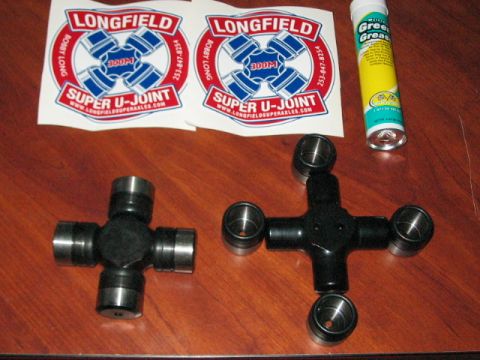 1991 Ford Bronco - Two u-joints and a tube of grease are laid out on a wooden table, with Longfield Super U-Joint stickers in the background.