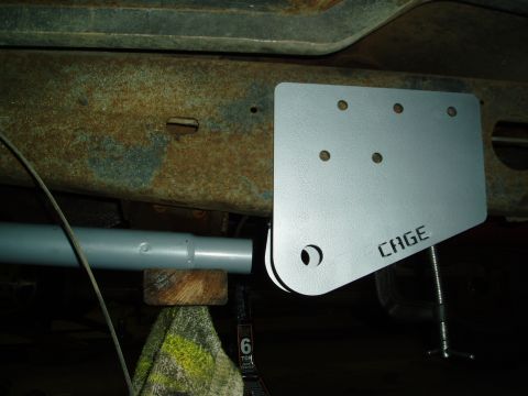 1994 Ford Bronco - A close-up view of a "CAGE" bracket being installed on a vehicle's frame, showing significant rust on the frame.