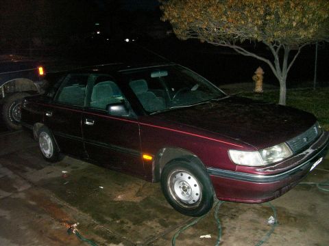 1991 Ford Bronco - A maroon sedan is parked in a driveway at night, with a tree and fire hydrant nearby.