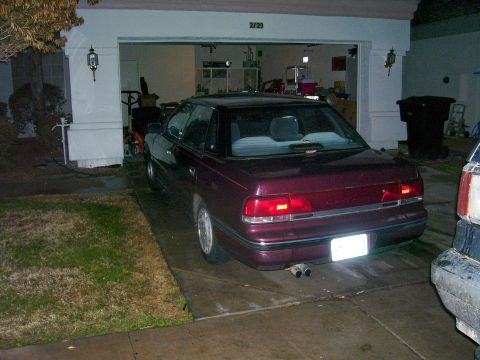1991 Ford Bronco - Maroon sedan with dual exhaust pipes parked in a driveway, with a garage in the background.