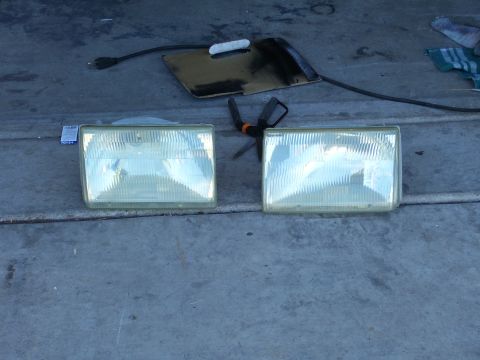 1991 Ford Bronco - Pair of car headlights on concrete, with tools and electrical cord in background.